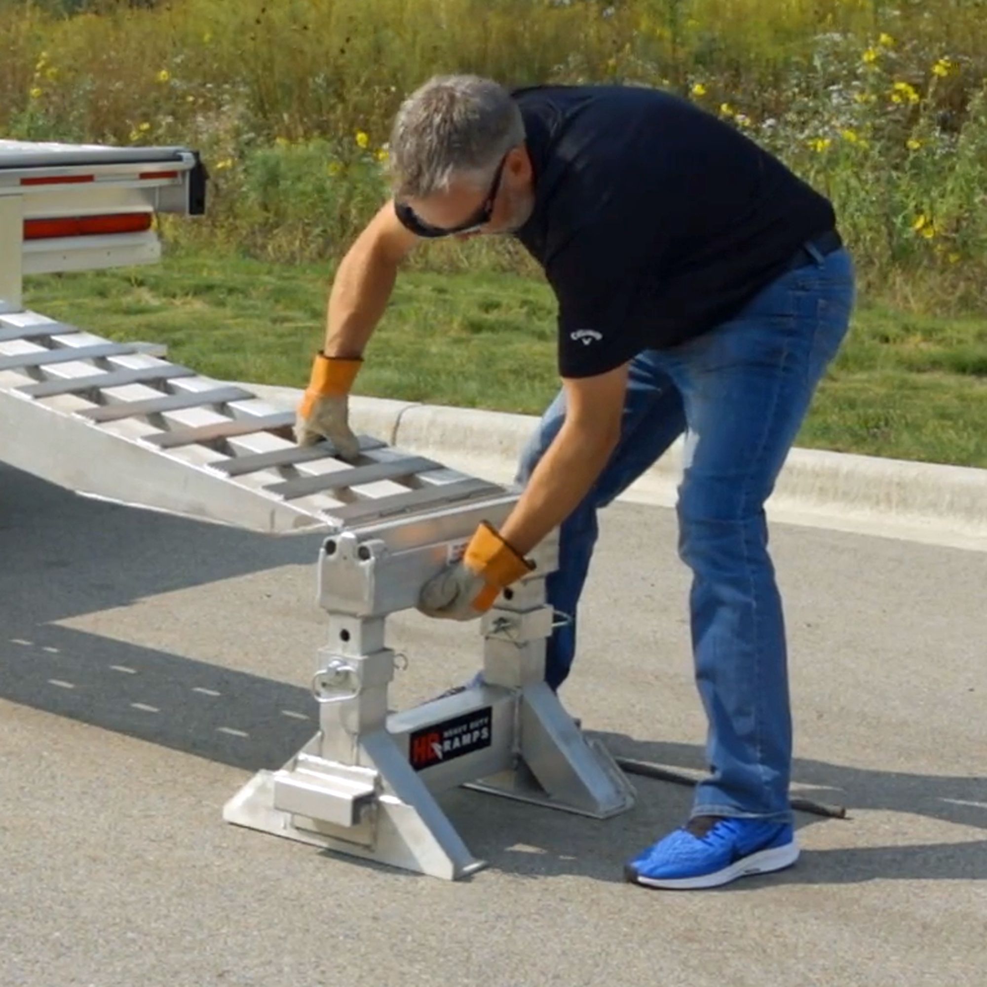 Man placing HD Ramps loading ramps onto a ramp support stand