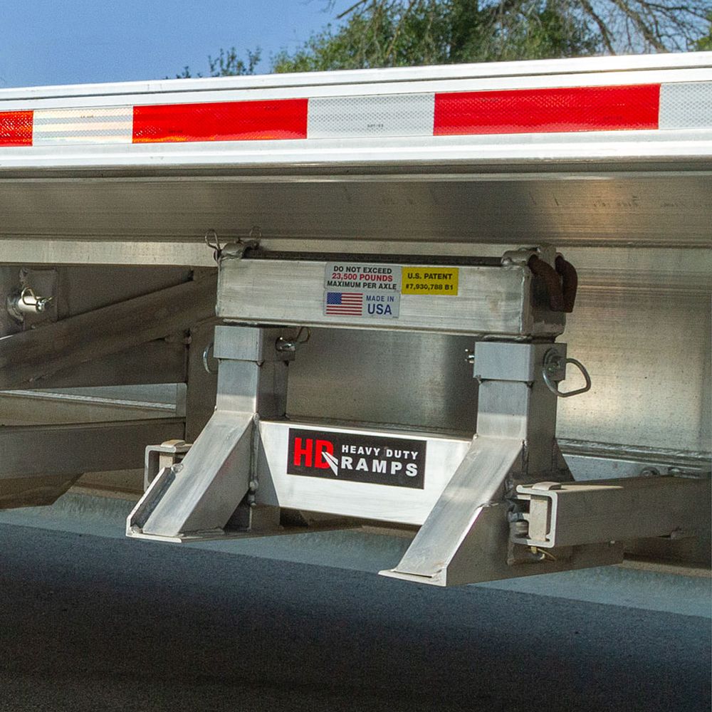 HD Ramps support stand stored in a pair of suport stand storage brackets under a step deck trailer