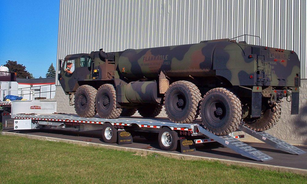 military vehicle loading onto a step deck trailer